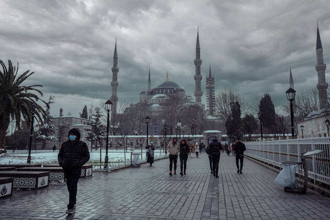People walk past a mosque on a cloudy day