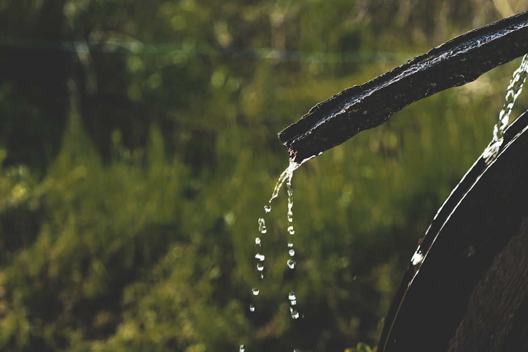 Water dripping from a dark pipe onto a surface.